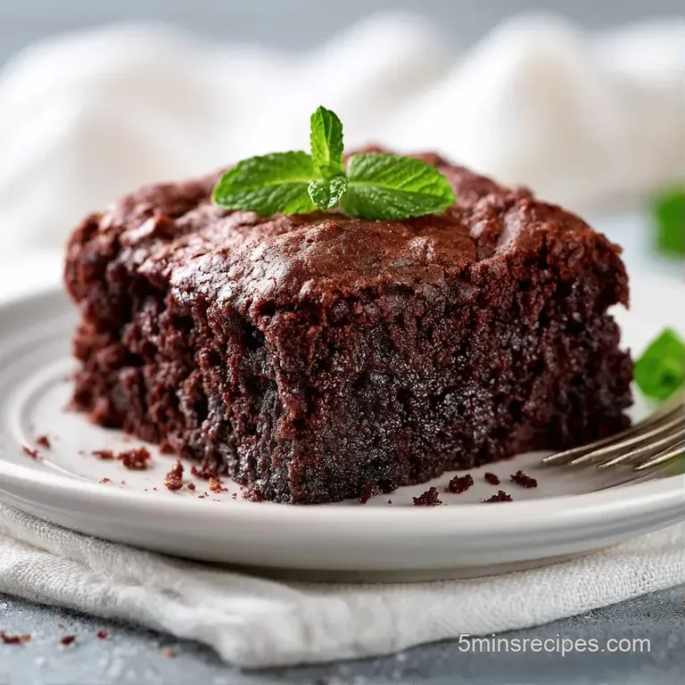 Square of fudgy chocolate cake dusted with powdered sugar on a white plate, paired with fresh red raspberries.