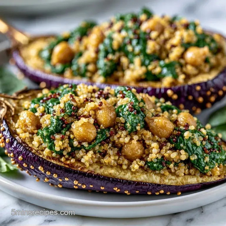 Sliced roasted eggplant halves filled with vibrant grains and diced vegetables on a minimalist white porcelain plate.
