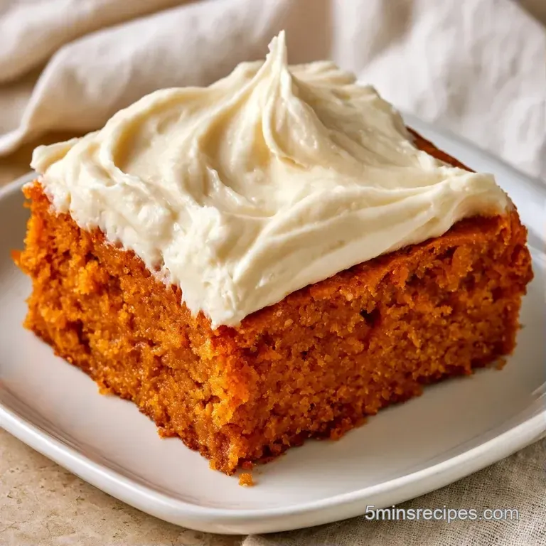 A neat square of spiced orange cake topped with a swirl of white frosting, plated on a white ceramic dish with mint.