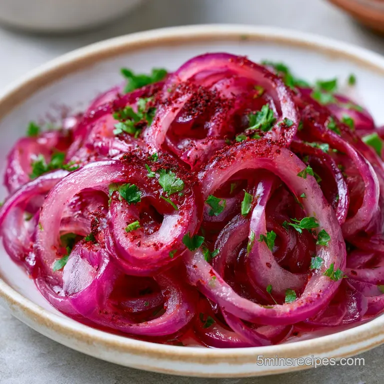 Thinly sliced crimson onion rings arranged in a neat heap on a white platter, dusted with deep reddish-purple spice.